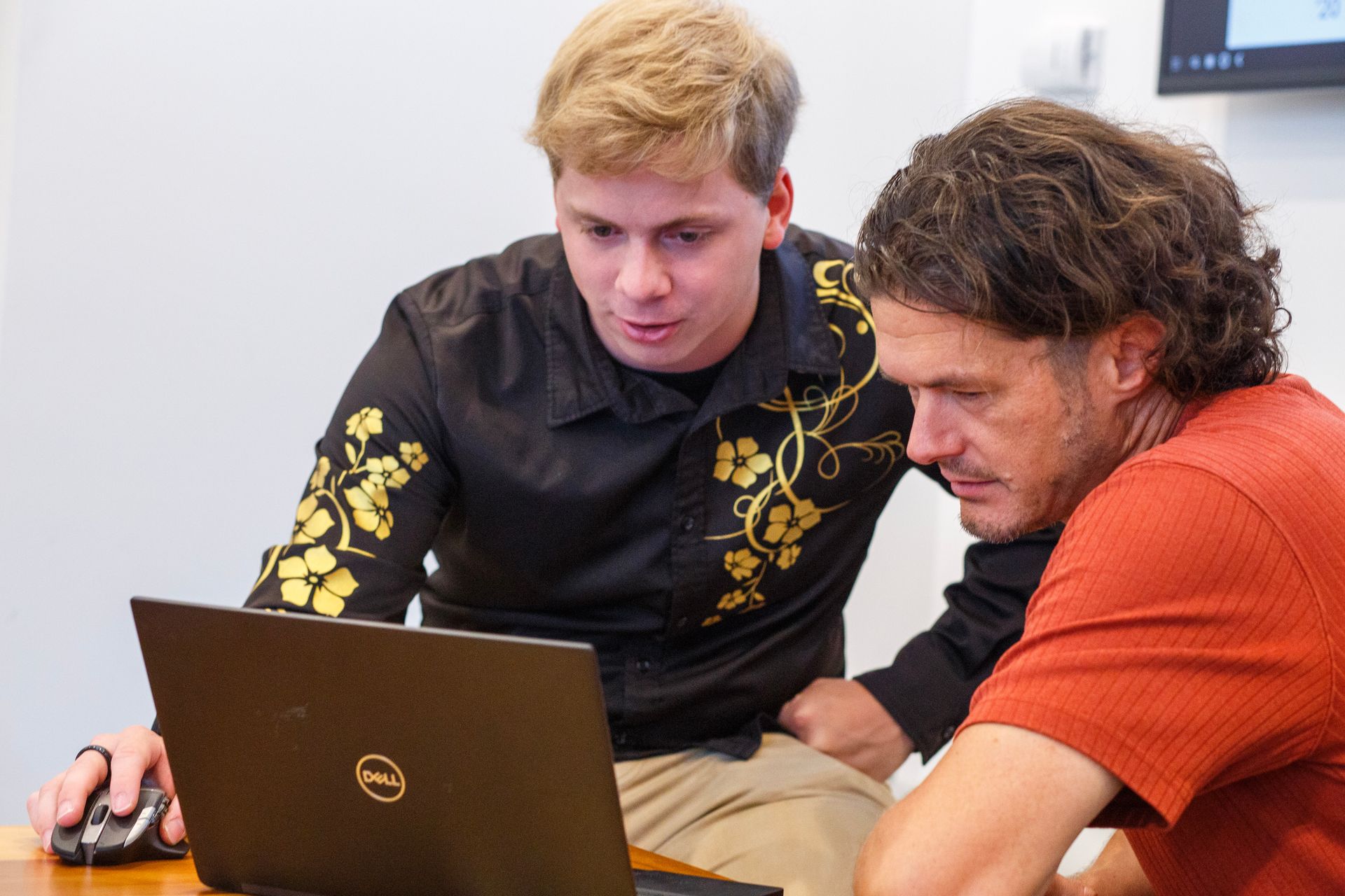 Two men are looking at a laptop together.