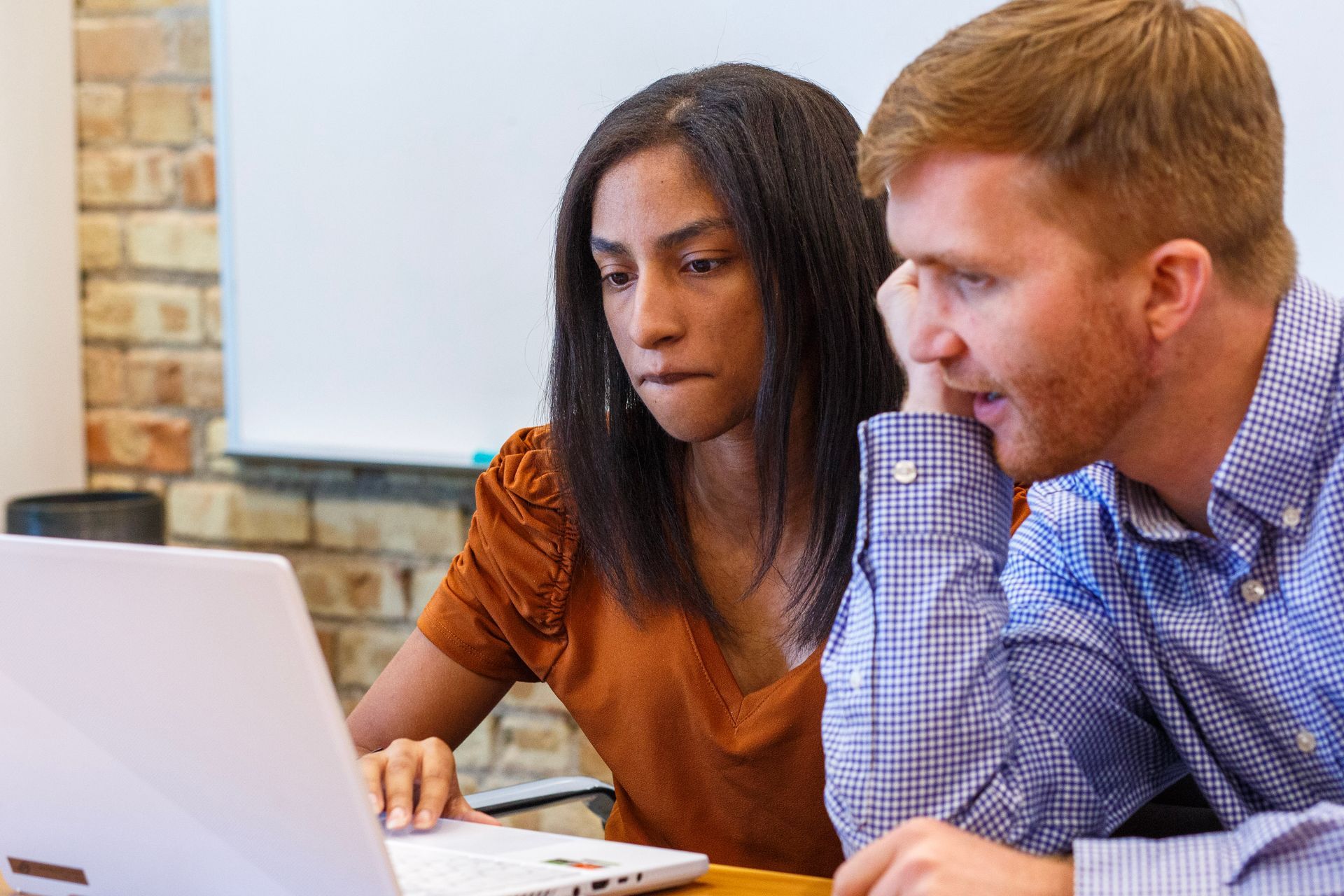A man and a woman are looking at a laptop computer.