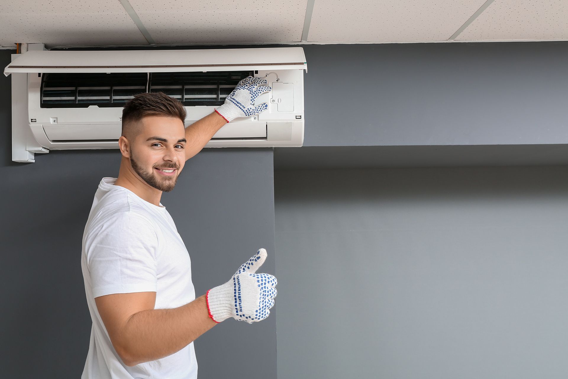 A technician installing an air conditioner indoors.