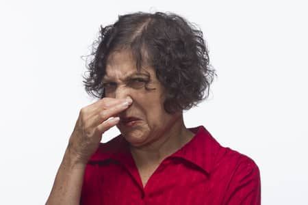Woman in a red shirt pinching her nose Woman in a red shirt pinching her nose