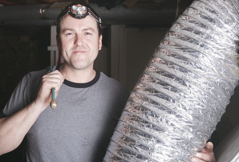 Man with headlamp holding silver flexible ductwork