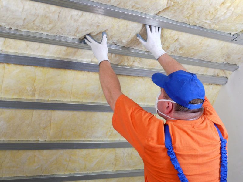 Man in safety gear installing insulation Man in safety gear installing insulation