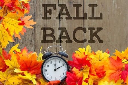 Alarm clock surrounded by colorful fall leaves