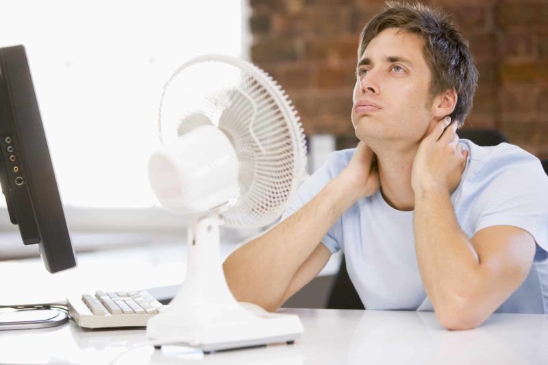 Man on his desk with a fan Man on his desk with a fan