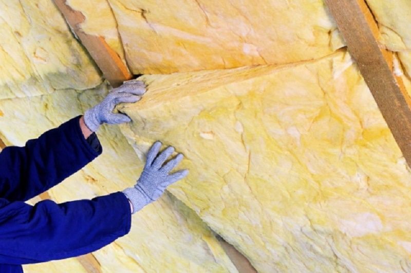 Person wearing gloves installing yellow insulation Person wearing gloves installing yellow insulation