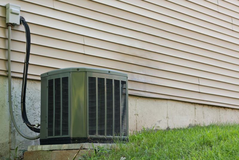 Air conditioning unit against a house with tan siding Air conditioning unit against a house with tan siding