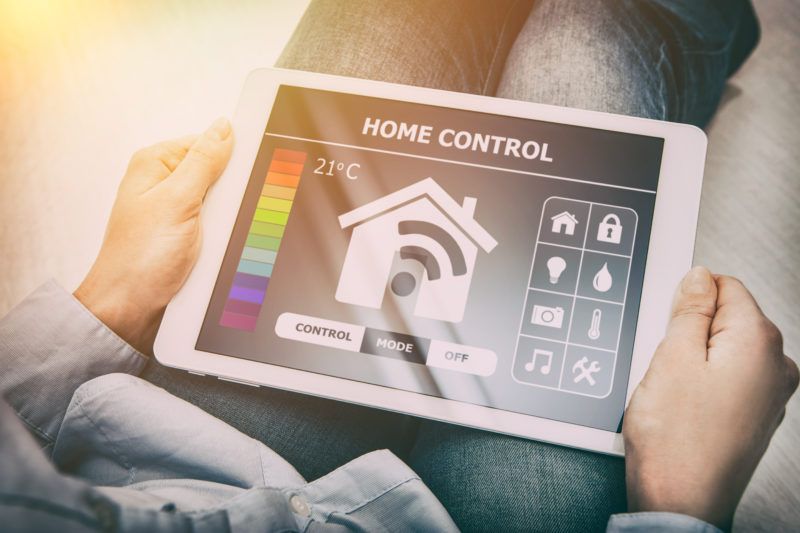 Person holding tablet displaying a Home control interface Person holding tablet displaying a Home control interface