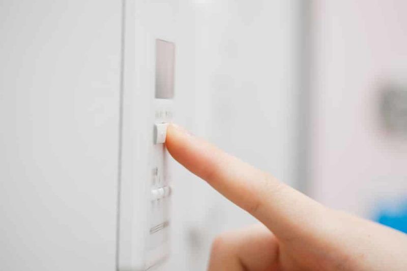 Finger presses a button on a white appliance control panel Finger presses a button on a white appliance control panel
