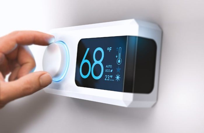 Hand adjusting a digital thermostat dial