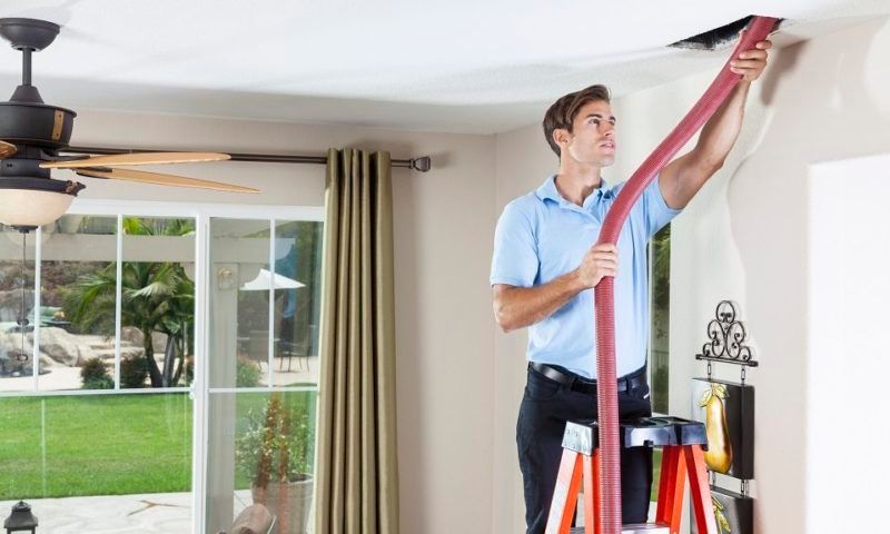 Man on ladder cleaning a ceiling vent Man on ladder cleaning a ceiling vent