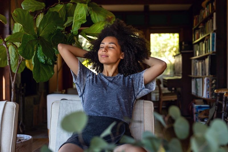 Woman relaxing in chair with hands behind head Woman relaxing in chair with hands behind head
