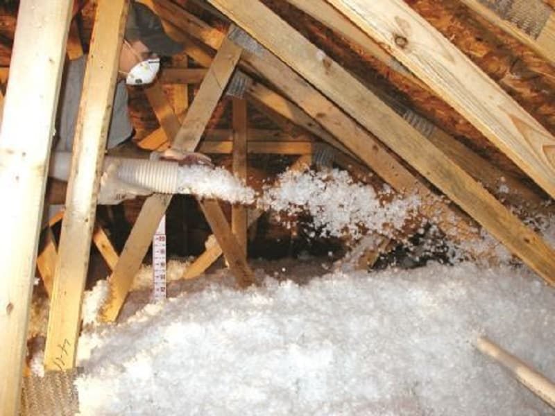 Attic with insulation being blown in through a hose Attic with insulation being blown in through a hose
