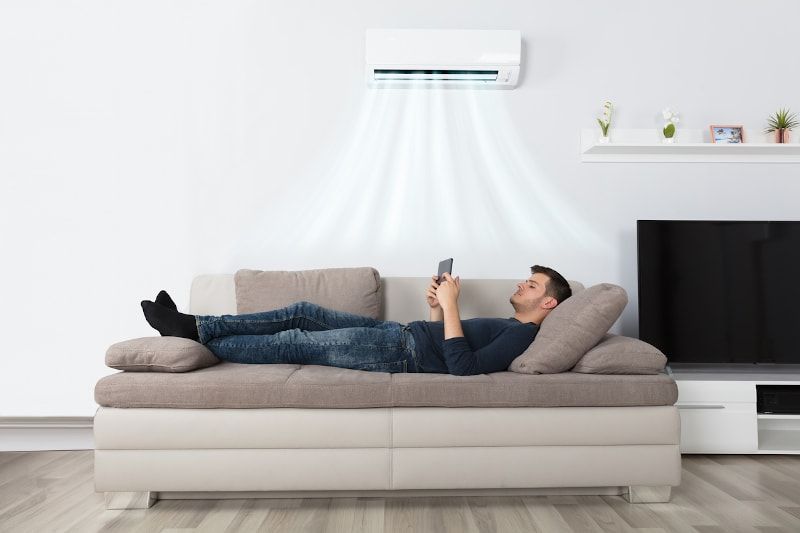 Man under cool air from wall-mounted AC unit