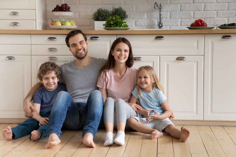 Happy family of four sitting on a kitchen floor Happy family of four sitting on a kitchen floor