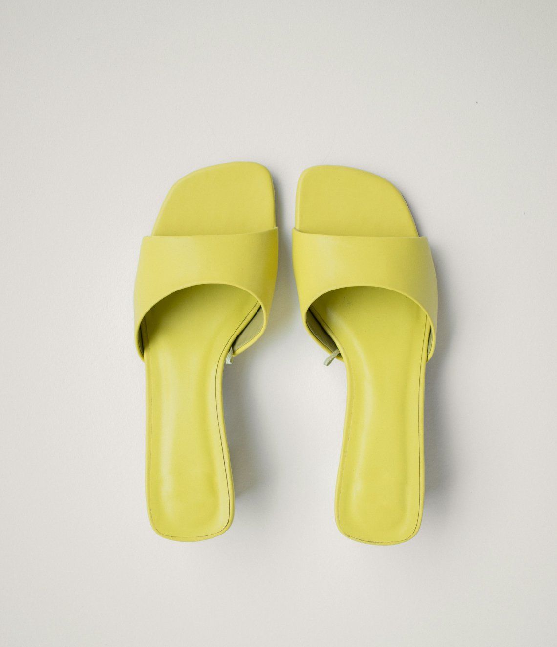 A pair of yellow sandals on a white surface