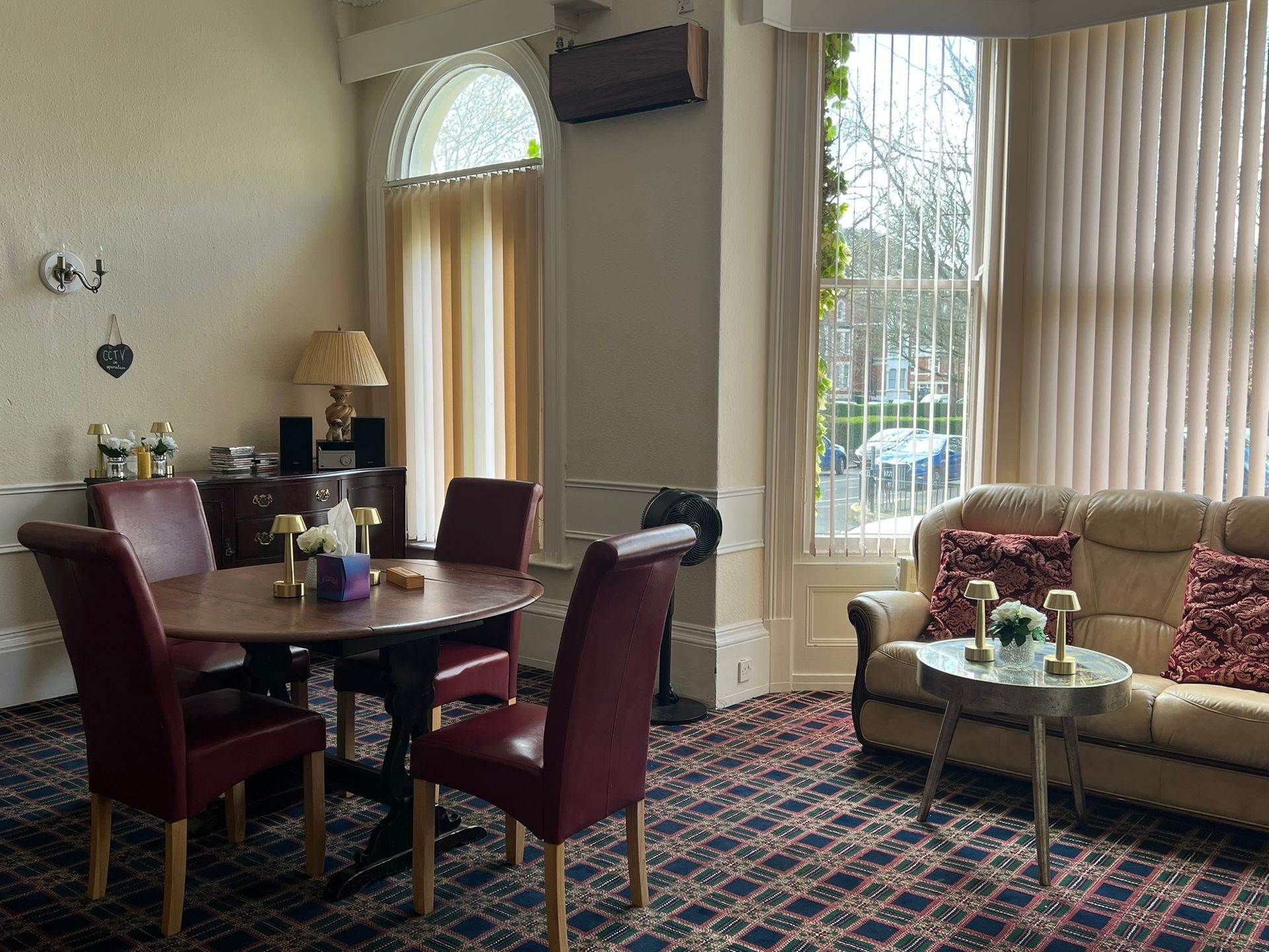 Bright living room with dining table, sofa, large windows, and patterned carpet