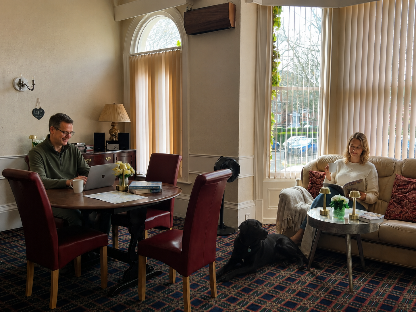 Couple relaxing in the Carlton House sitting room with their dog resting nearby.
