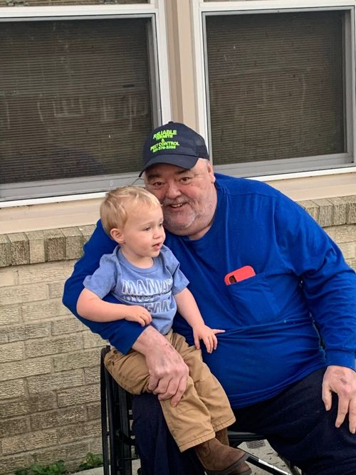 Founder Kenneth Walters wearing a Reliable Termite & Pest Control cap, holding his great-grandson