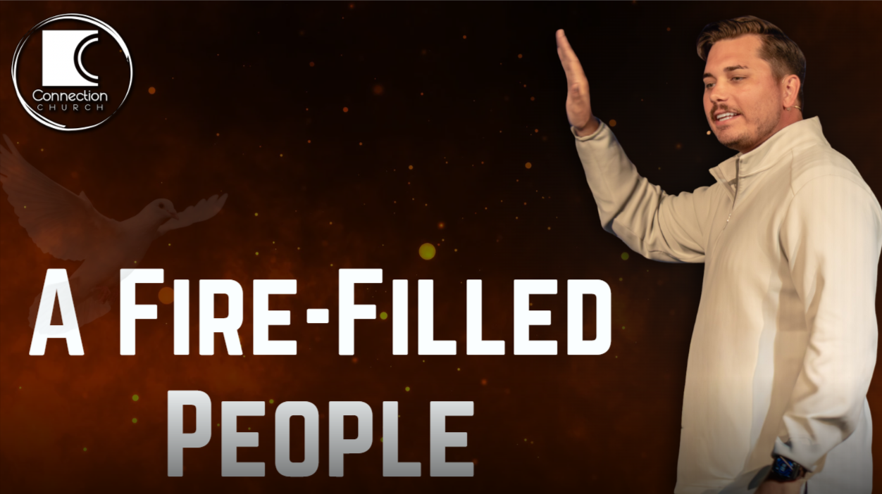 Man speaking on stage beside text: “A FIRE-FILLED PEOPLE” on a dark red background