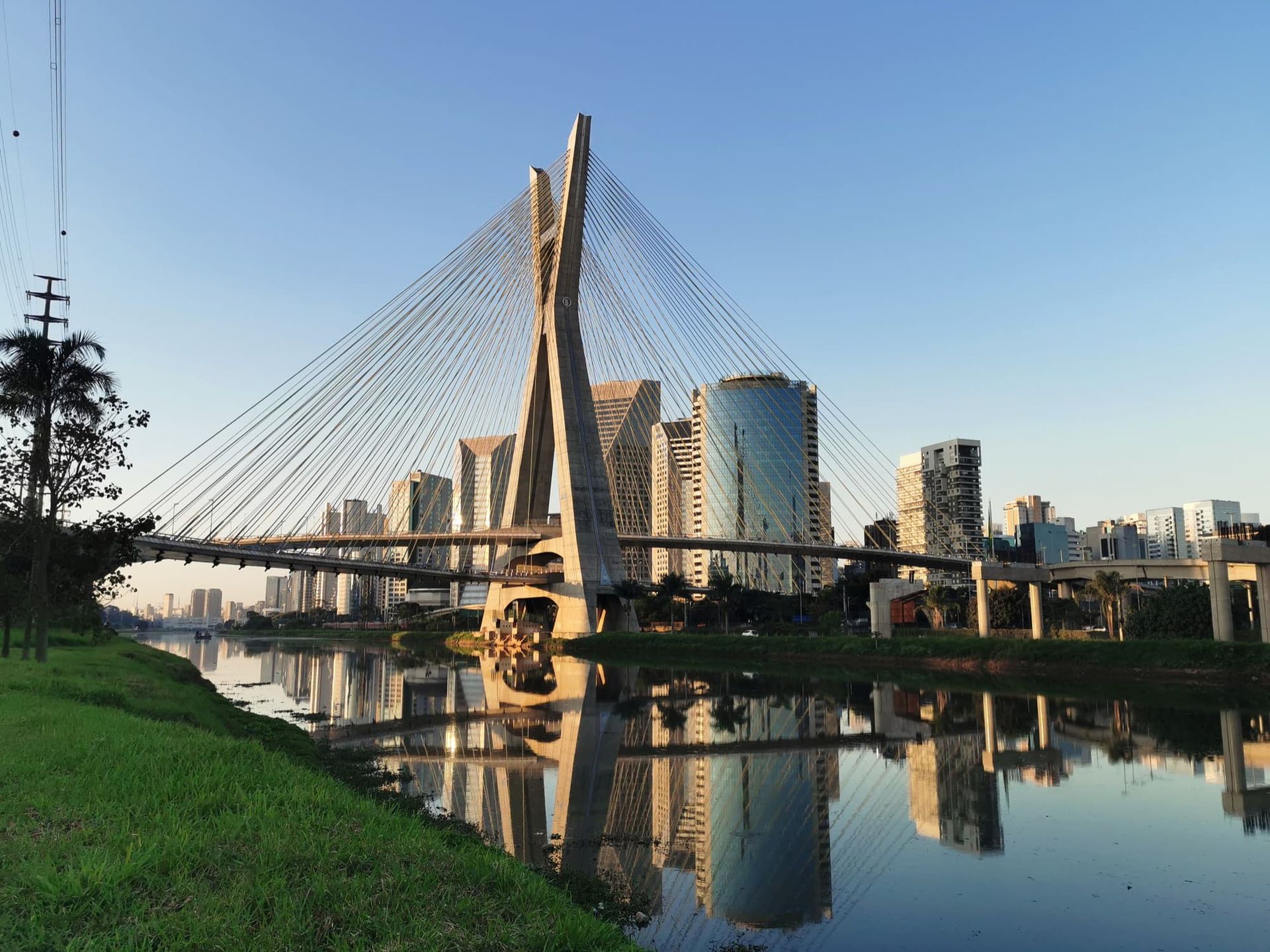 The Octavio Frias de Oliveira bridge over the Pinheiros River in São Paulo, reflecting in the water at sunset.