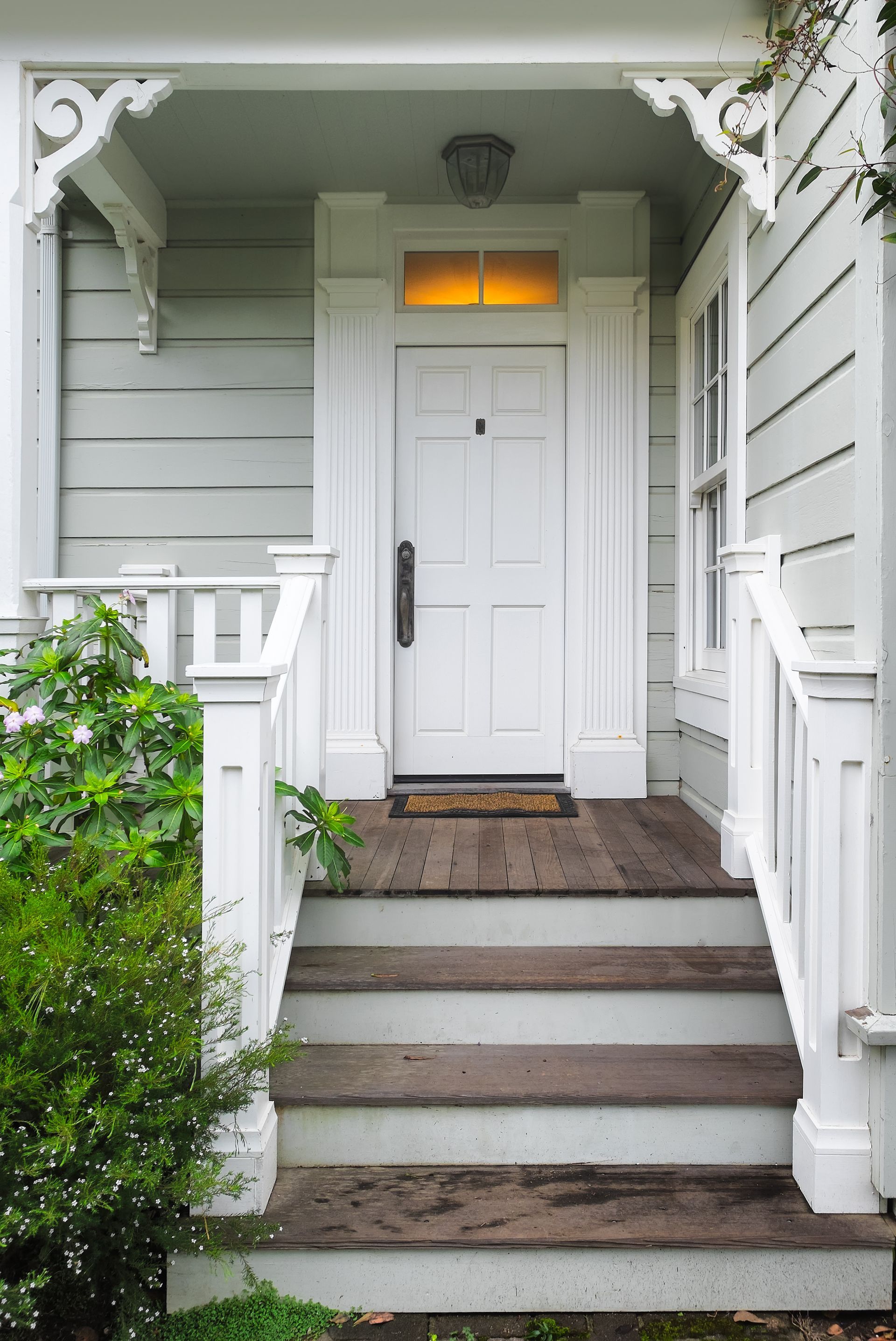 White house entrance with steps, door, porch railing and ornate trim. White house entrance with steps, door, porch railing and ornate trim.