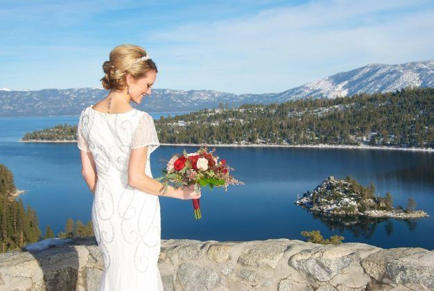 Bride with bouquet overlooking a lake and snow-capped mountains. Sunny day.