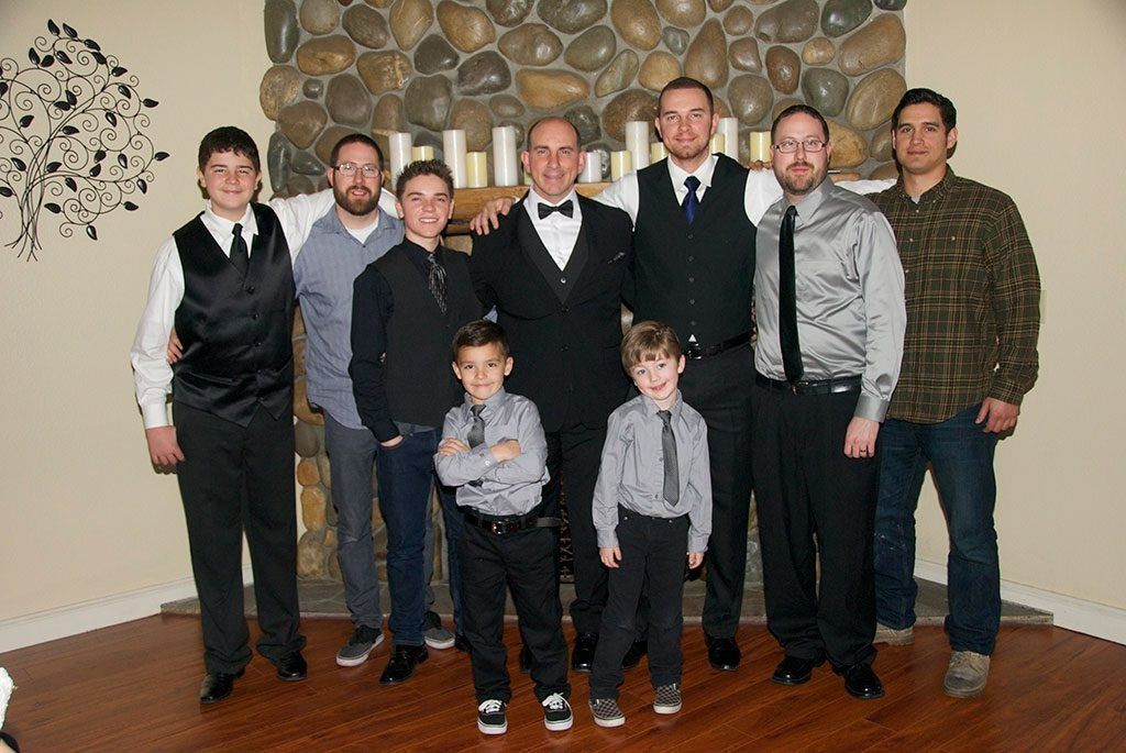 Group of people in formal attire pose in front of a stone fireplace.
