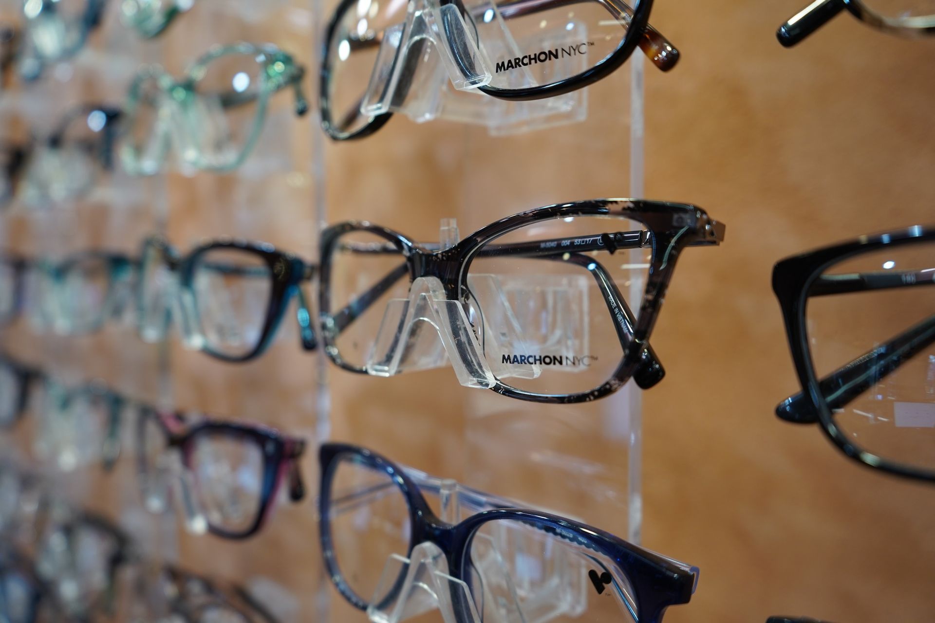 Rows of eyeglass frames displayed on a store wall in various colors and styles