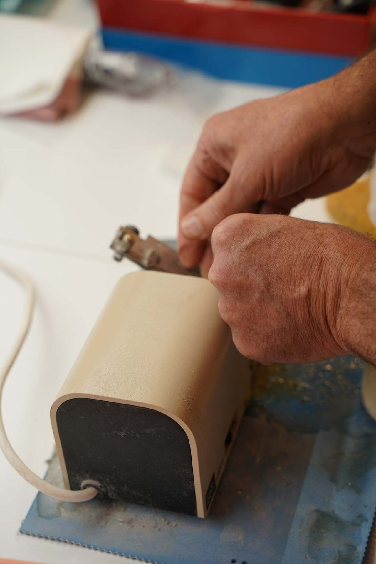 Hands shaping a beige foam block with a small tool on a workbench