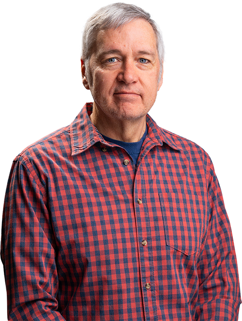 Man in a red plaid shirt standing against a white background, facing forward with a neutral expression