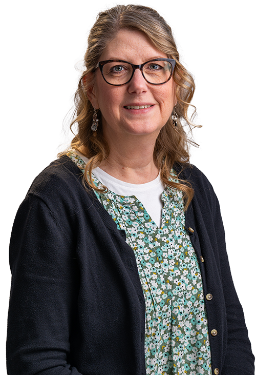 Portrait of a smiling woman with glasses, wearing a green patterned blouse and dark cardigan on a white background