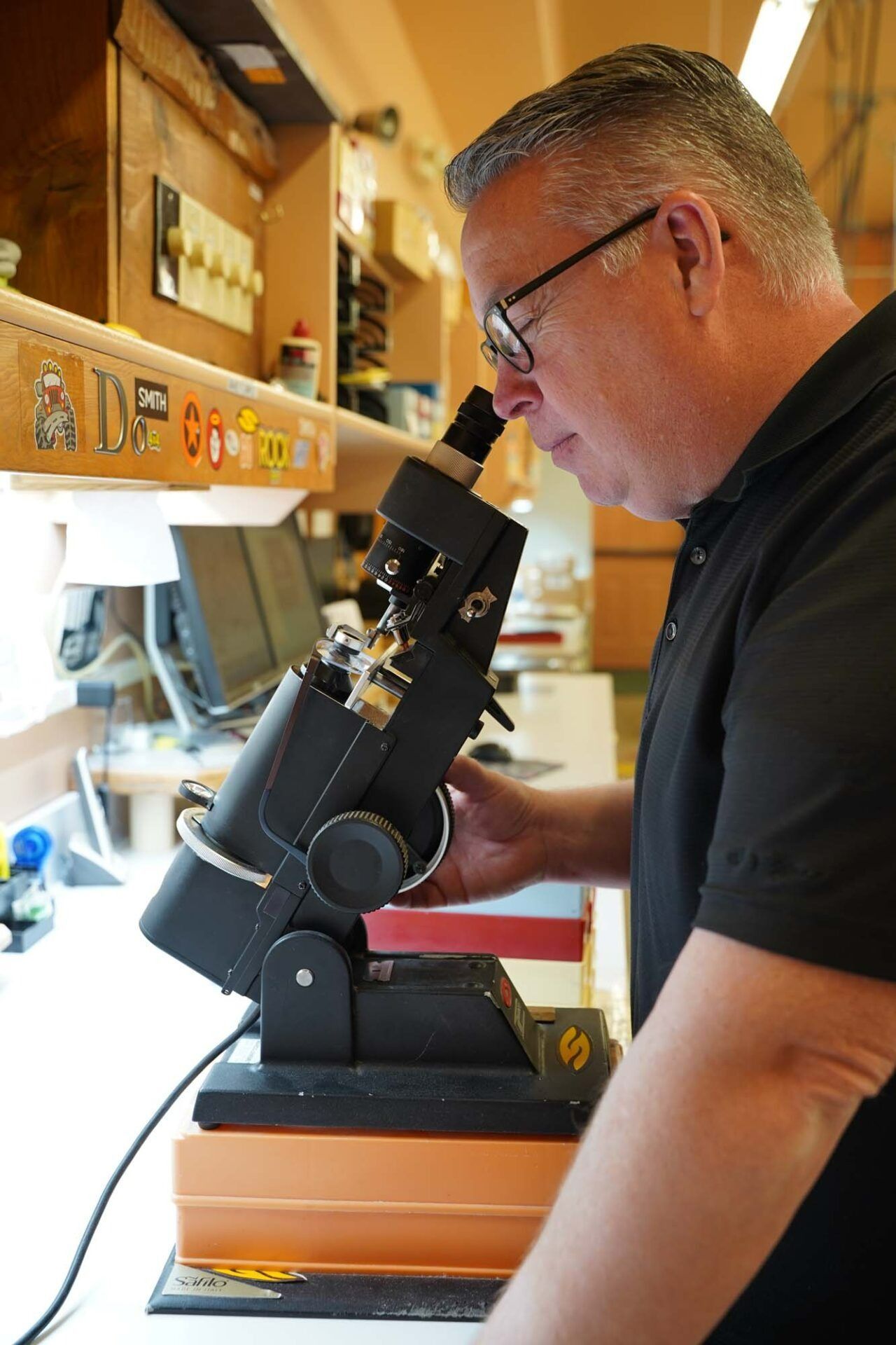Man using a microscope at a workbench in a bright room