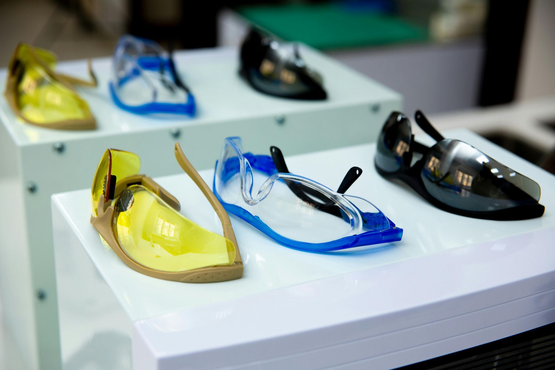 Colorful sunglasses displayed on white shelves: yellow, blue, and black frames.