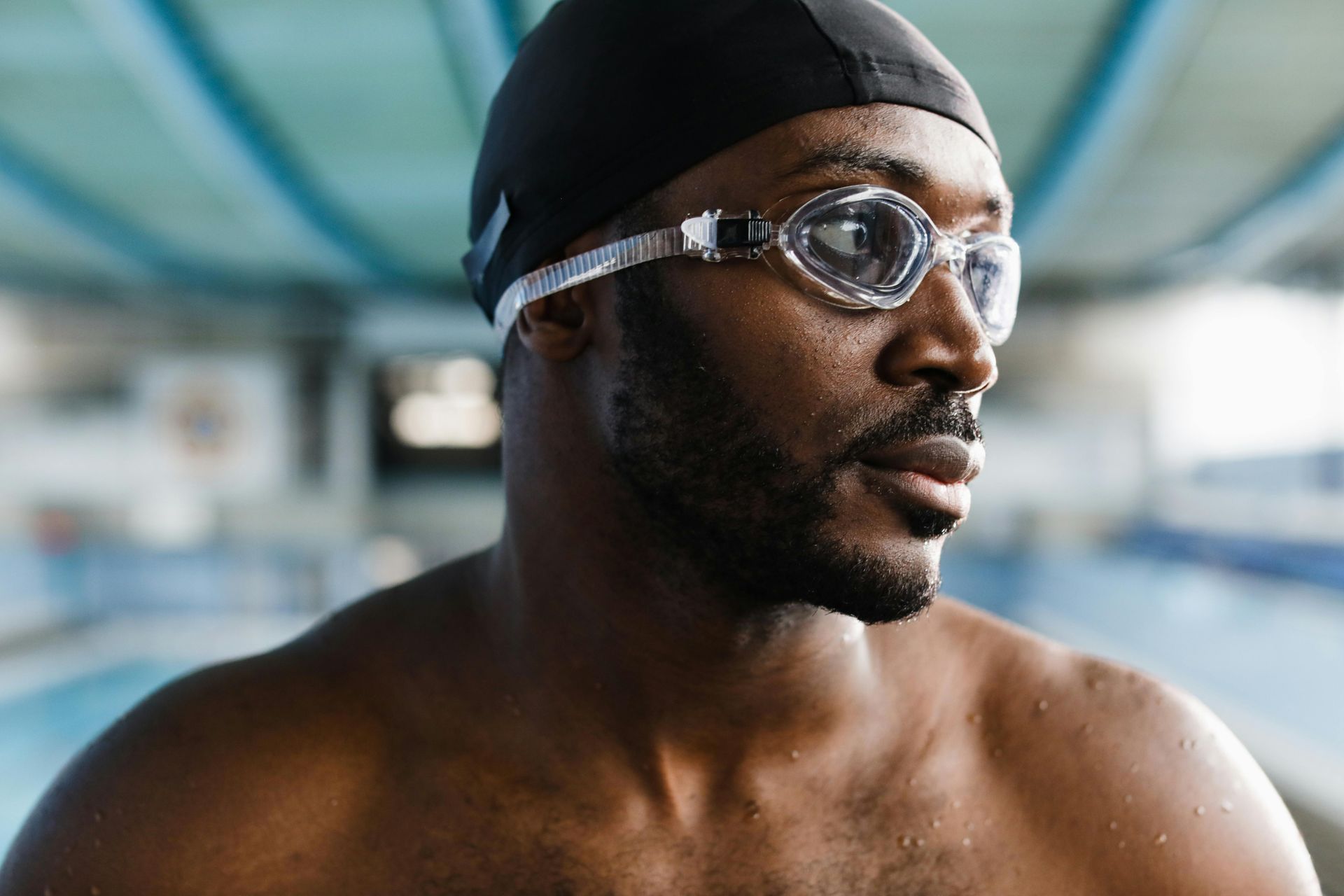 Swimmer in goggles and cap looking to the side at an indoor pool