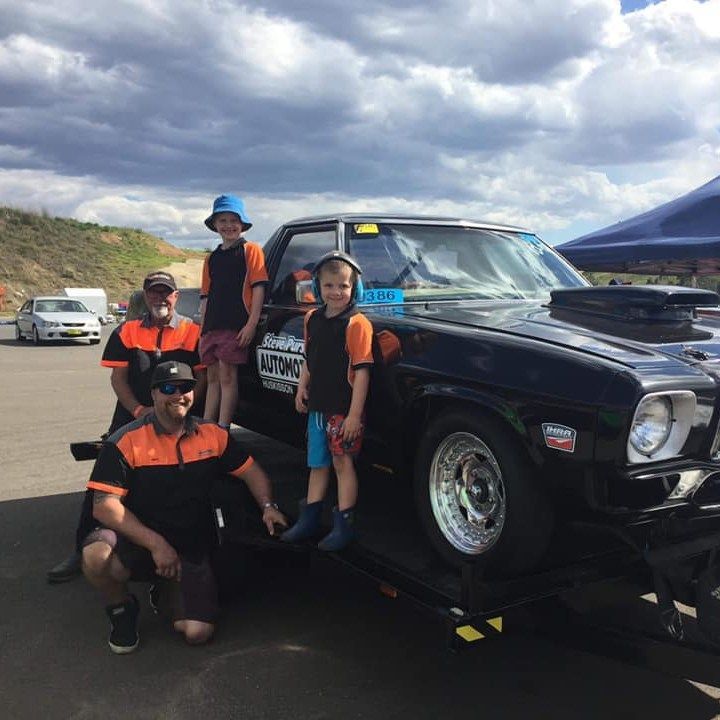 A Group of People Posing in Front of A Truck that Says Motorsport — Steve Purse Automotive In Woollamia, NSW