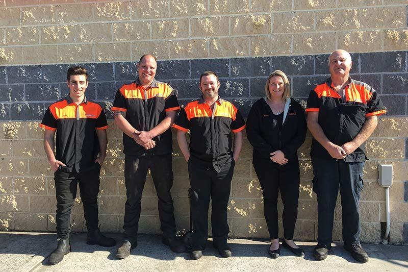A Group of People Standing in Front of A Brick Wall — Steve Purse Automotive In Jervis Bay, NSW
