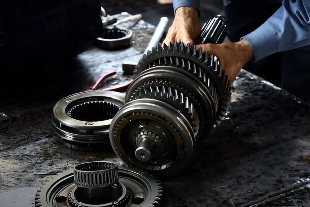 A Man Is Working on A Gearbox on The Floor — Steve Purse Automotive In Huskisson, NSW

