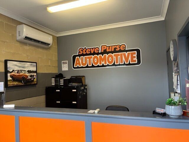 A Steve Purse Automotive Sign Hangs on A Wall Above a Counter — Steve Purse Automotive In Huskisson, NSW
