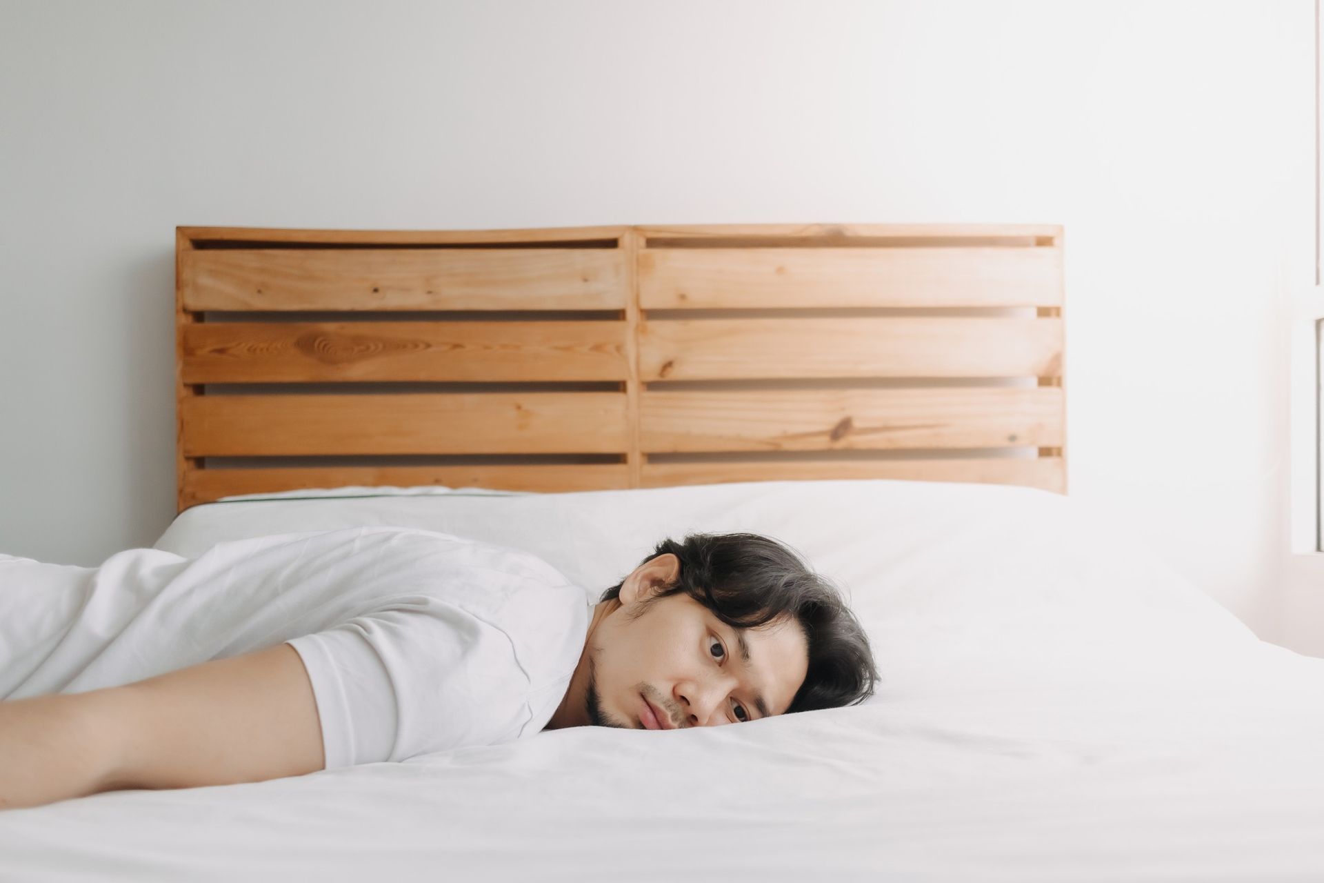 a man is laying on a bed with his head on the pillow .
