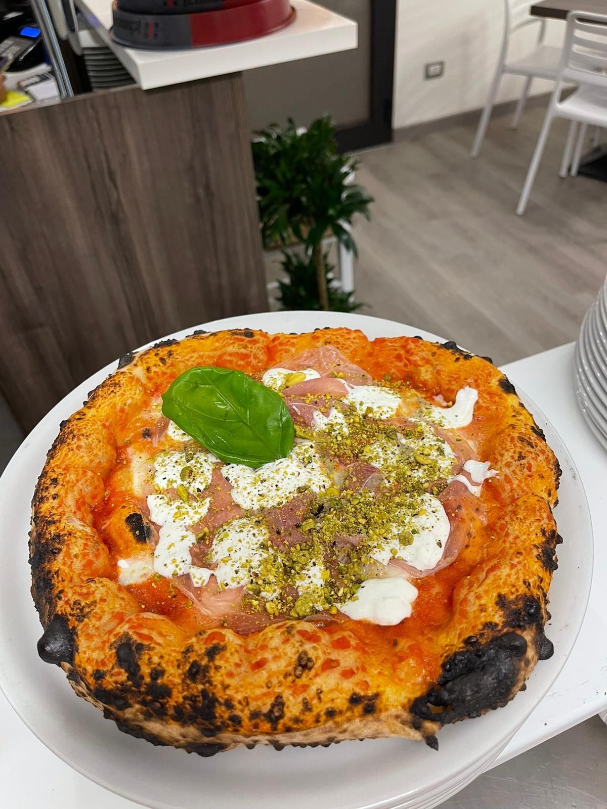 Una pizza condita con salsa di pomodoro, formaggio bianco cremoso, sottili fette di carne, pistacchi tritati e basilico.