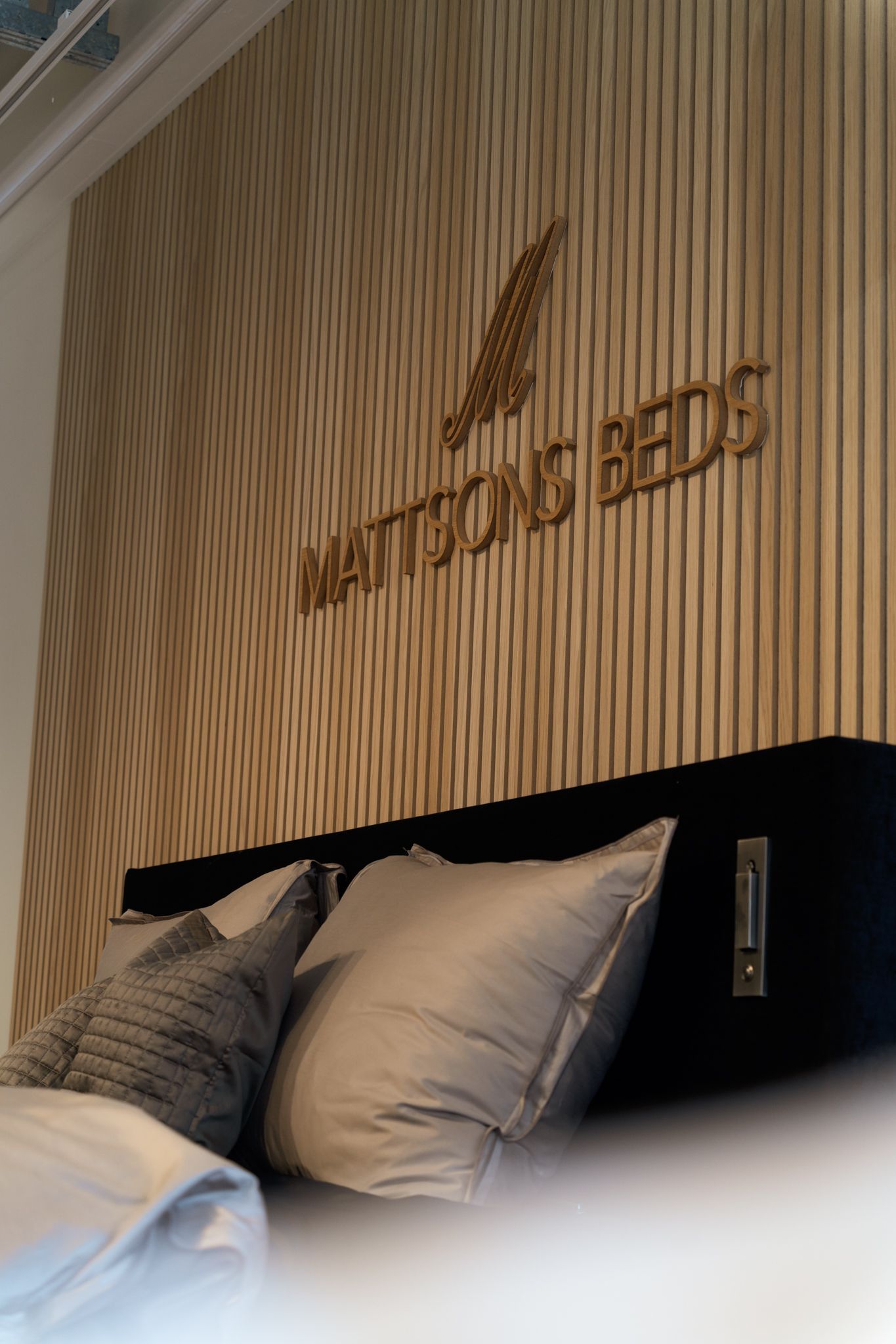 Slaapkamer met houten accentmuur en "Mattsons beds"-bordje boven het bed.