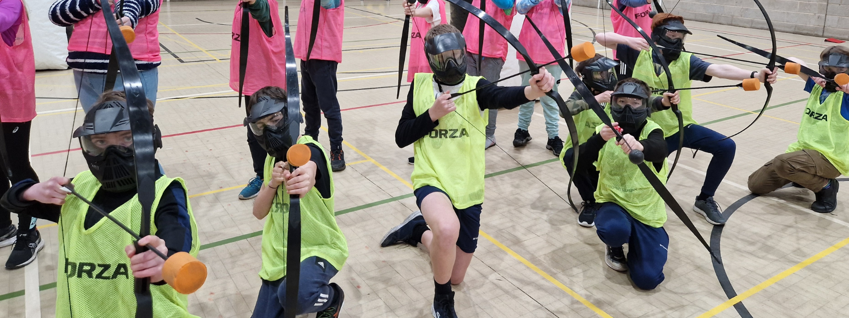Group of secondary students on an indoor rewards day event playing combat archery