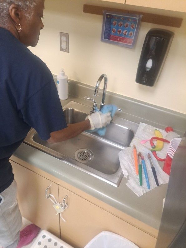 Person washing dishes at a stainless-steel sink in a kitchen.