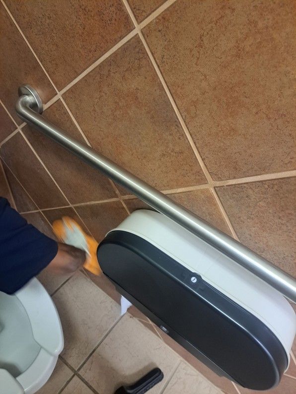 Bathroom floor with wall-mounted grab bar and toilet paper dispenser beside a toilet.