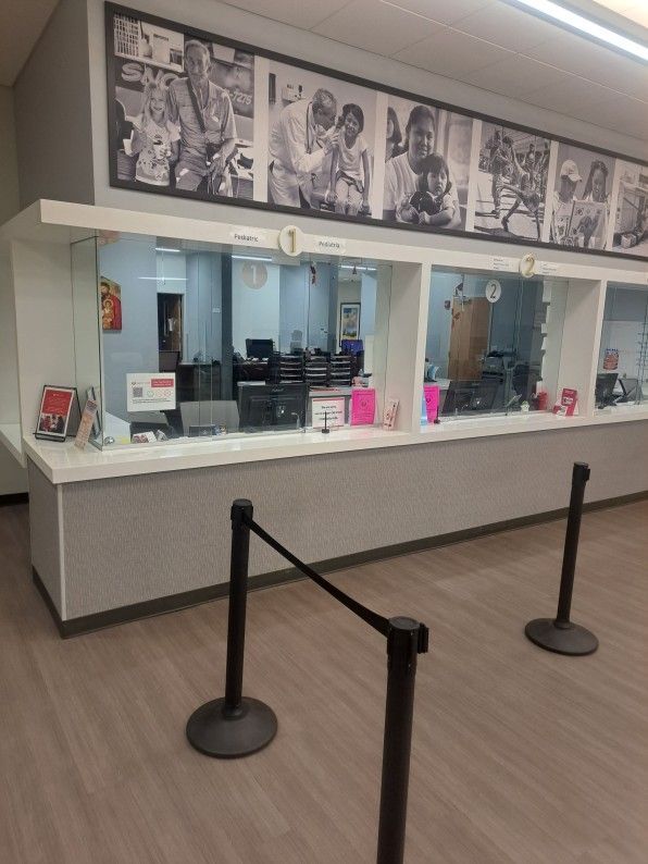 Empty ticket counter with glass windows, black stanchions, and black-and-white photo panels above.