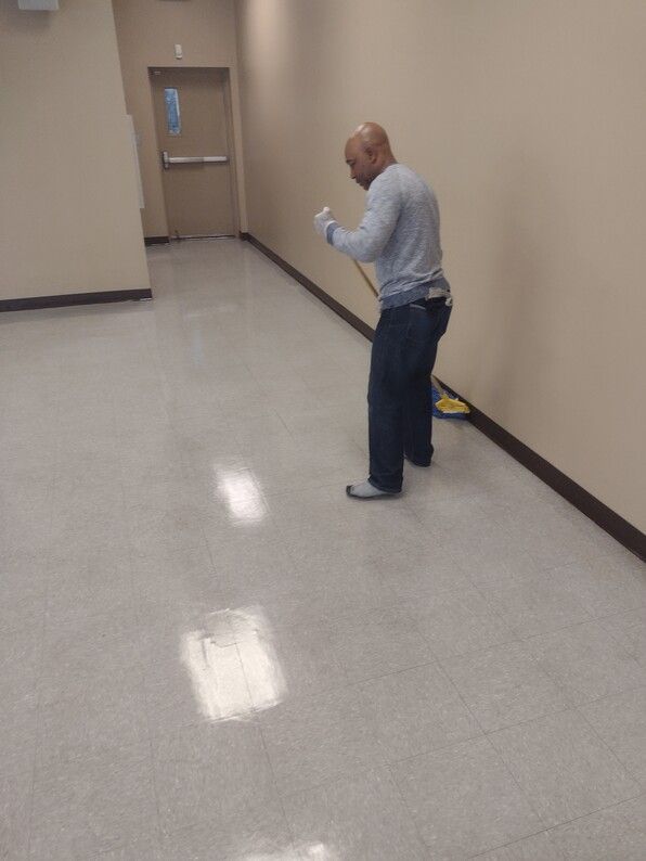 Person standing in a hallway, looking at a phone near a closed door.