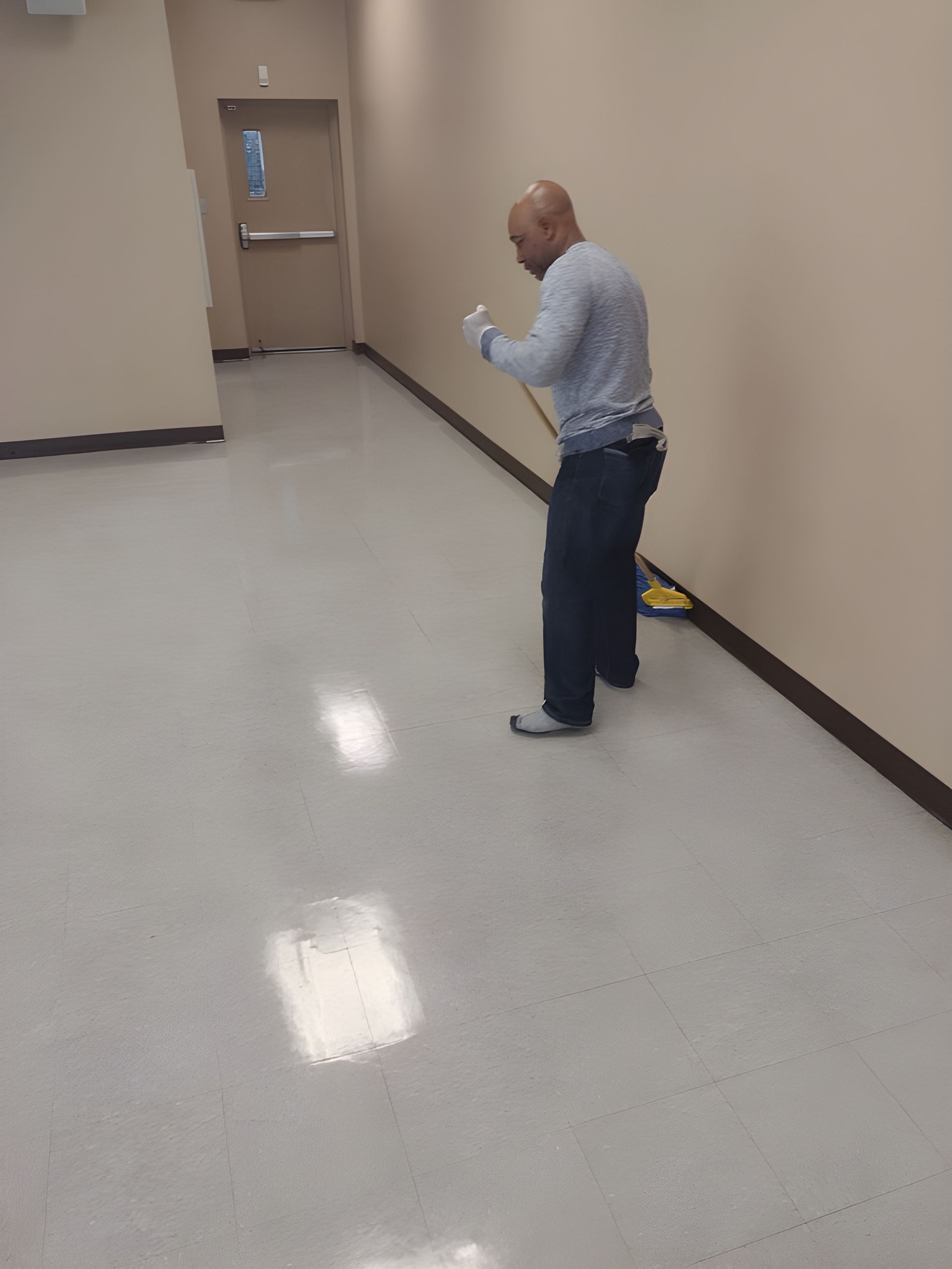 Person standing in a hallway looking at a phone near a closed door.