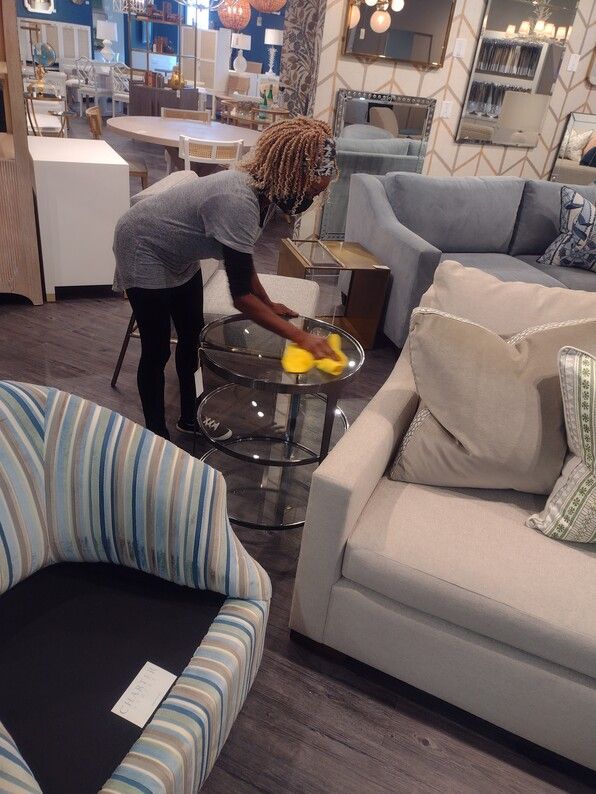 Person arranging a glass bowl of yellow fruit on a coffee table in a modern living room