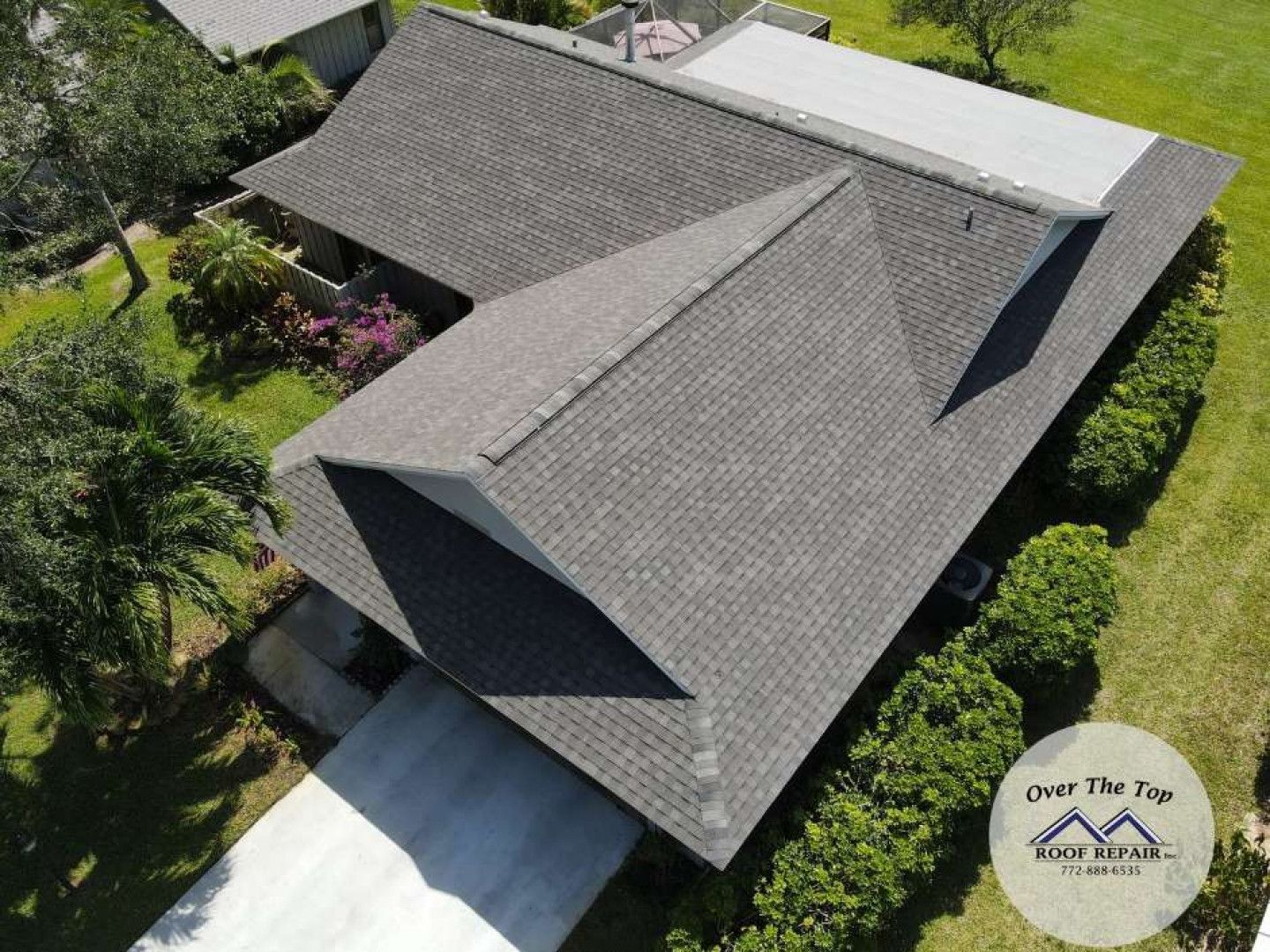 An aerial view of a house with a gray roof and a driveway.