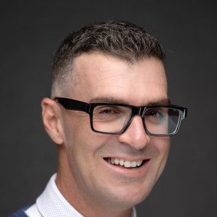 A man wearing glasses is smiling for the camera.